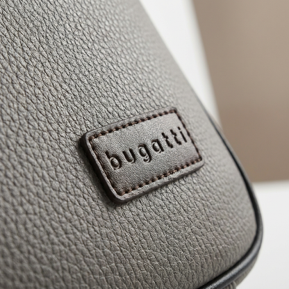A macro close-up of the brown Bugatti logo and its stitching on the grey pebble grain vegan leather briefcase, showcasing the detailed texture and high-quality craftsmanship.