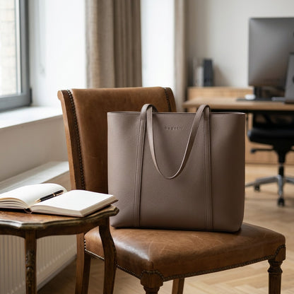 Bugatti Pure Business taupe leather tote bag resting on a leather armchair in a contemporary office context.