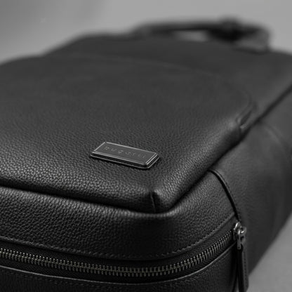 Macro detail of the Bugatti Contrast Backpack showing the pebble grain vegan leather and metal logo.