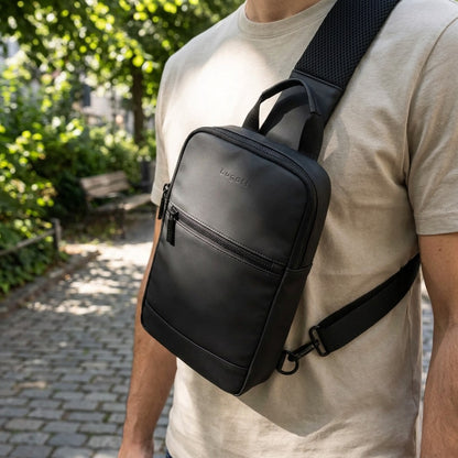 A person wearing the black Bugatti Mile End sling bag with matte water-resistant coating outdoors.