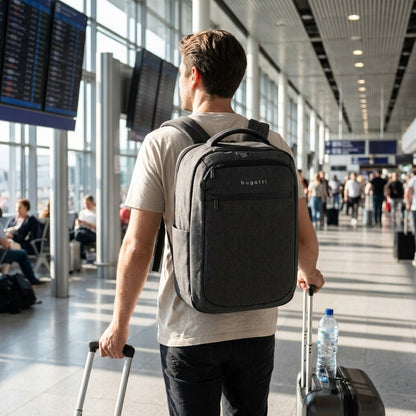 A person wearing a Bugatti Traveller charcoal laptop backpack while walking through an airport.