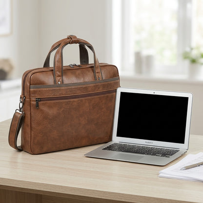 Cognac Bugatti Valentino vegan leather briefcase shown on a desk next to a 13-inch laptop for scale.