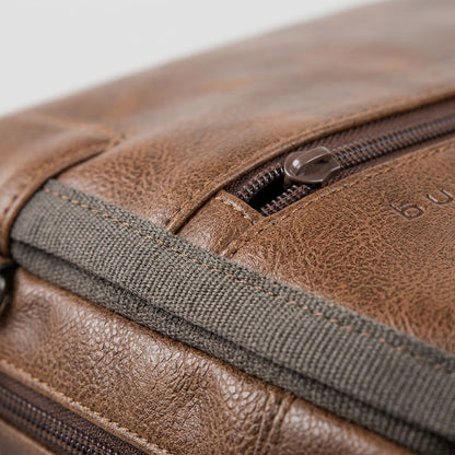 Macro detail of cognac vegan leather on a Bugatti Valentino Briefcase with stitching and zipper.