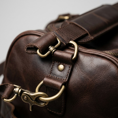 Macro view of the Mancini Leather Duffle Bag showing brass hardware, swivel hook, and grain texture.