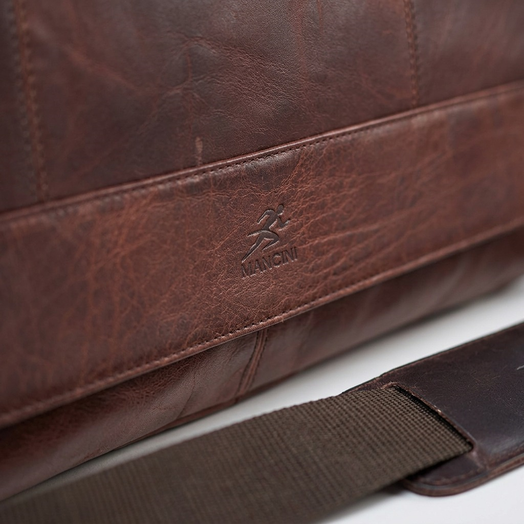Macro detail of the Mancini logo embossed on rich brown buffalo leather with precise stitching.