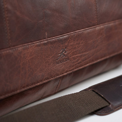 Macro detail of the Mancini logo embossed on rich brown buffalo leather with precise stitching.