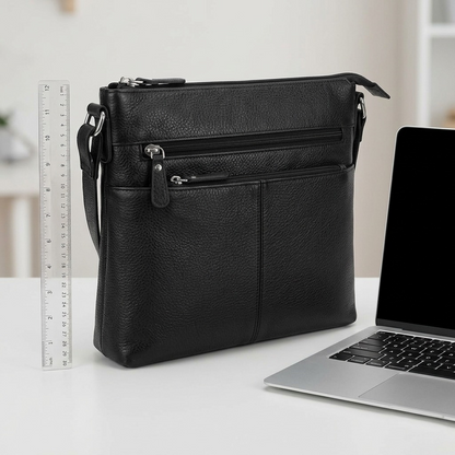 Black Mancini leather crossbody bag shown next to a 12-inch ruler and laptop for scale reference.