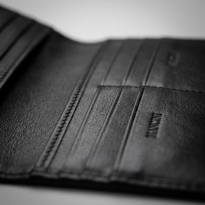 Macro detail of black Mancini leather wallet showing top-grain texture, card slots, and stitching.