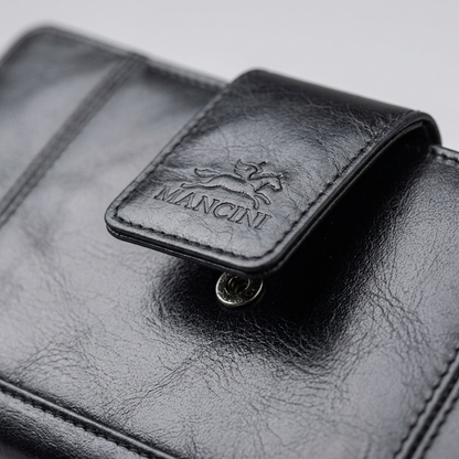 Macro view of black top-grain leather texture, Mancini embossed logo, and snap closure on a clutch.