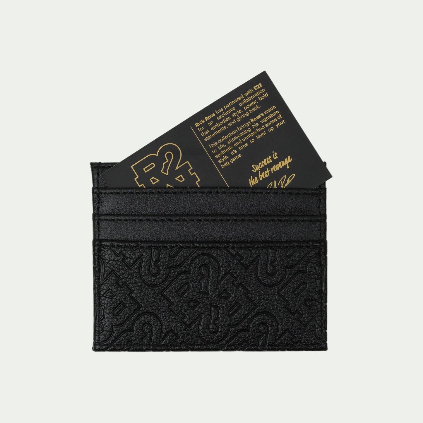 Black leather cardholder with embossed design and gold text on a white background