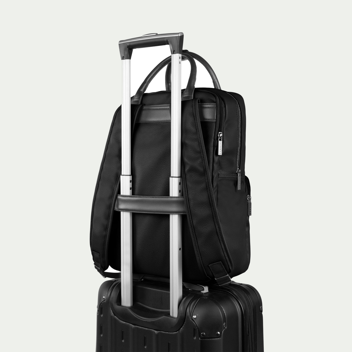 Bugatti Contrast backpack in black, secured to a suitcase handle with the rear luggage strap