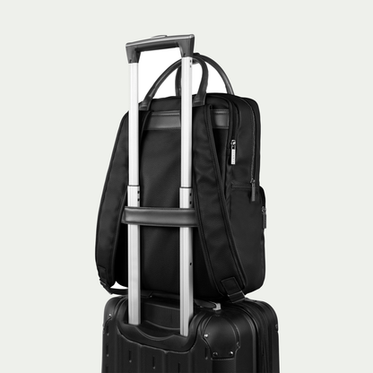 Bugatti Contrast backpack in black, secured to a suitcase handle with the rear luggage strap