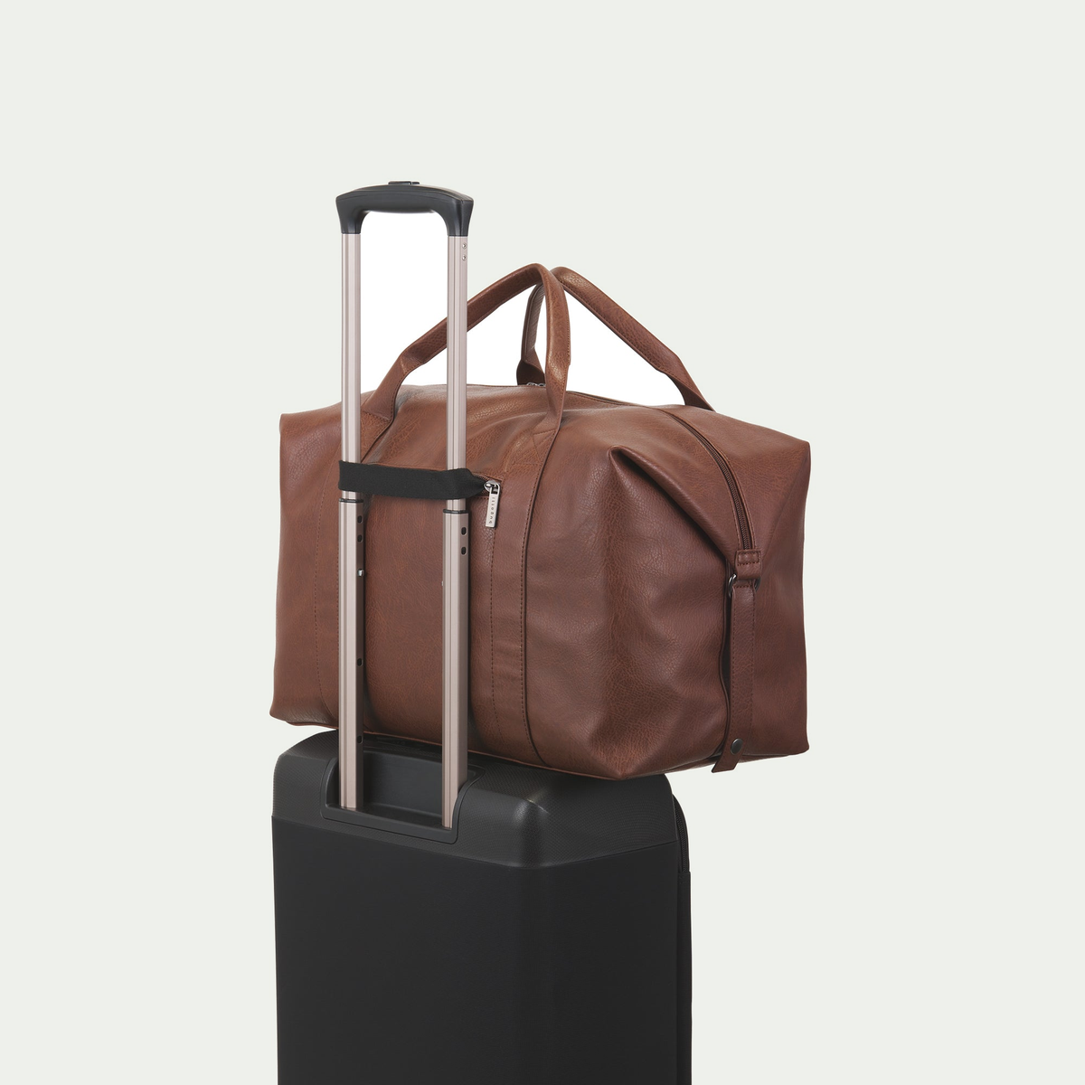 Bugatti Palermo duffle bag in cognac, secured to a suitcase handle with the rear luggage strap