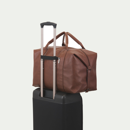 Bugatti Palermo duffle bag in cognac, secured to a suitcase handle with the rear luggage strap