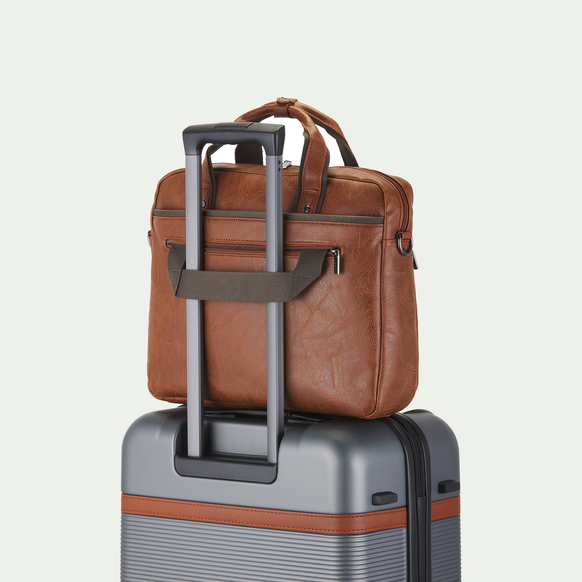 Bugatti Valentino briefcase in cognac, secured to a suitcase handle with the rear luggage strap