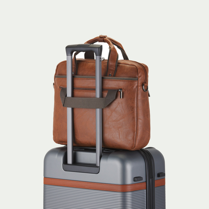 Bugatti Valentino briefcase in cognac, secured to a suitcase handle with the rear luggage strap